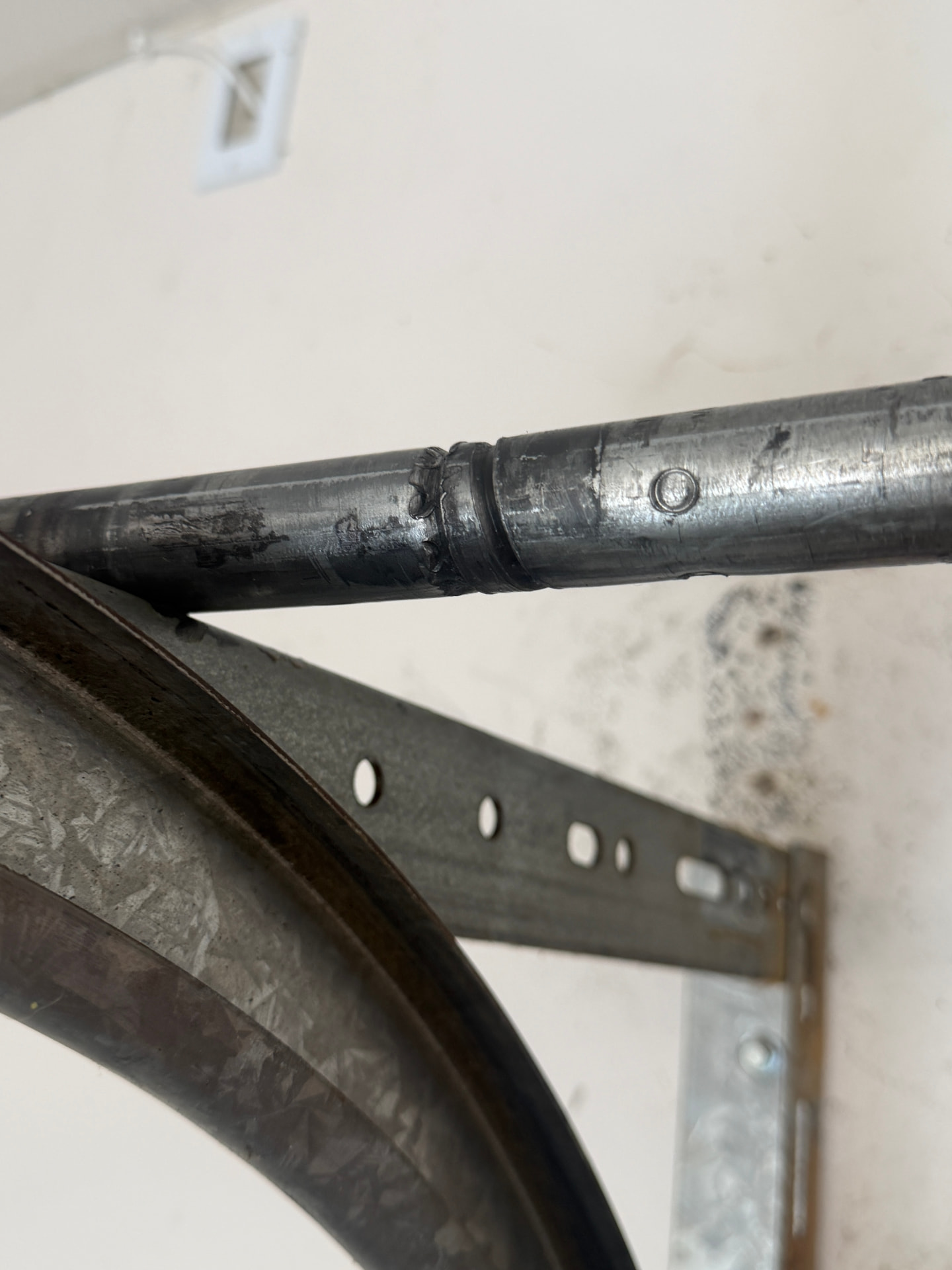 Worn garage door torsion shaft and track bracket before repair