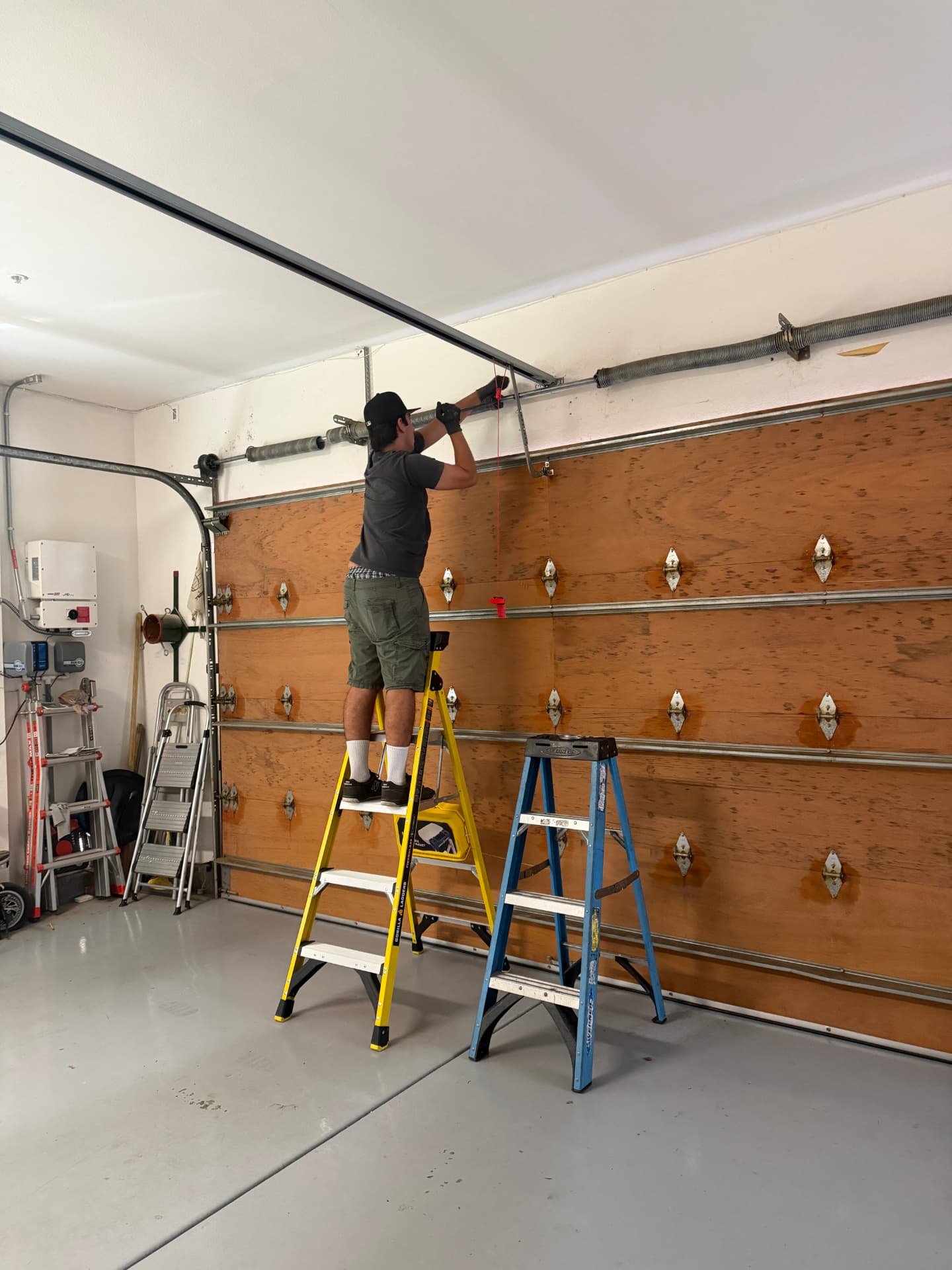 Technician adjusting garage door torsion springs
